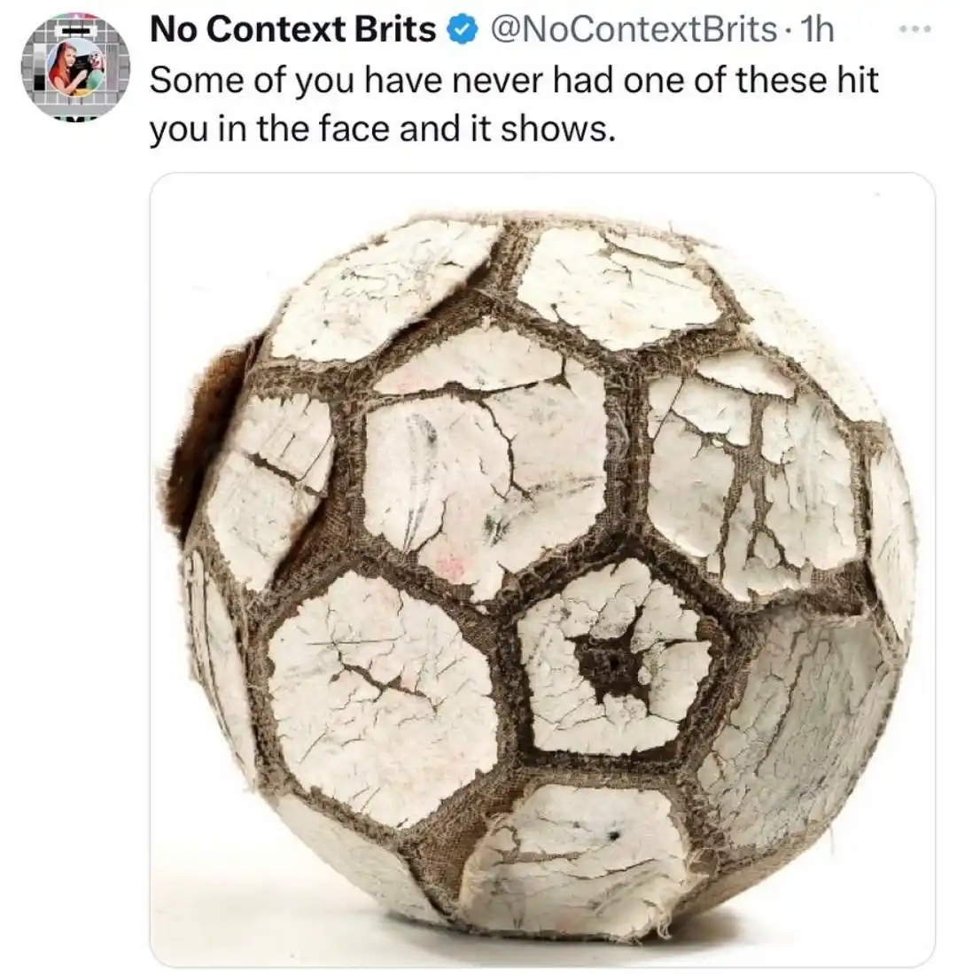 A close-up photo shows a very old, heavily worn, and cracked soccer ball with white panels and brown stitching, appearing…
