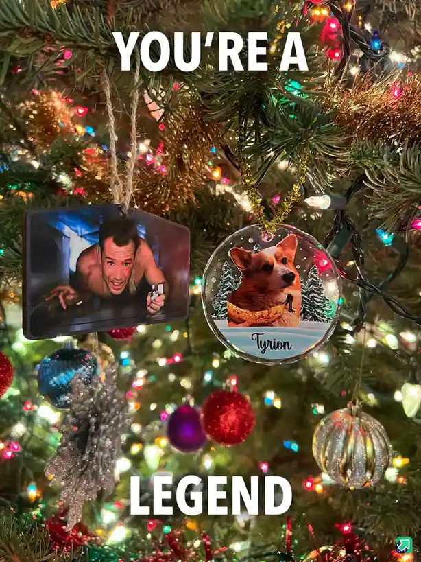 A close-up of a decorated Christmas tree with two ornaments hanging prominently: one is a rectangular photo of actor Johnny…