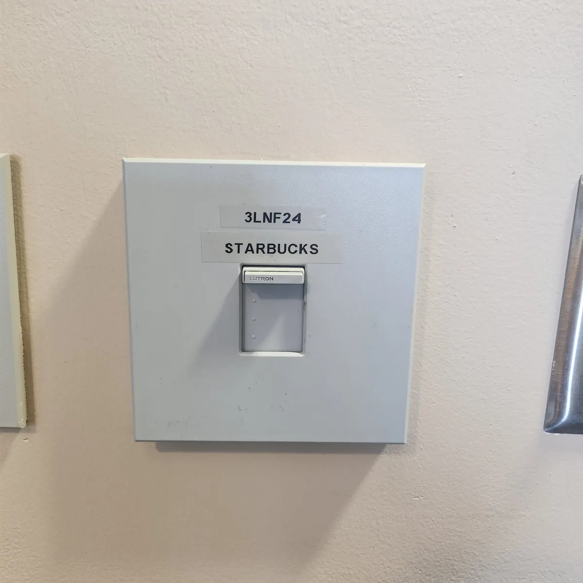 A close-up photo of a plain white light switch plate mounted on a textured wall, with two handwritten labels: '3LNF24' above…