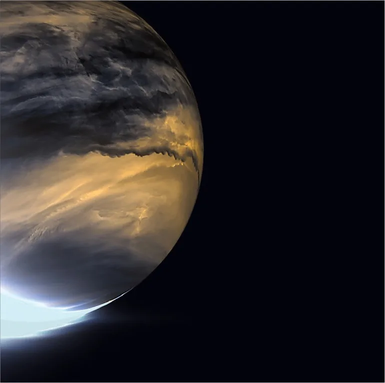 A view of the planet Venus showing its thick, swirling clouds with a bright limb glowing against the blackness of space. The…