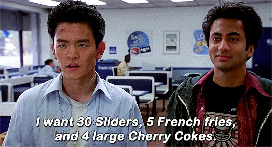 The image shows two rows of identical side-by-side panels featuring two men in a cafeteria. The man on the left has a…