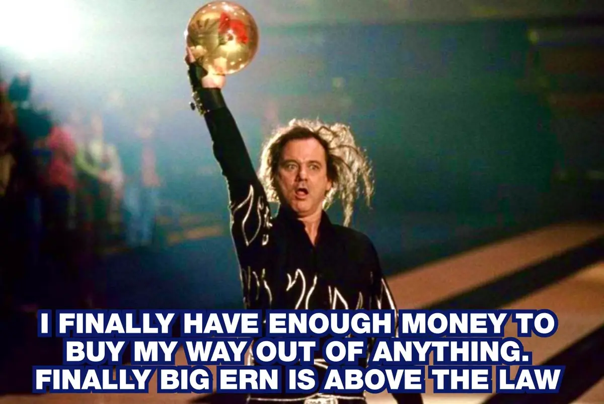 A man with wild hair, wearing a black outfit, triumphantly holds up a golden disco ball in a dimly lit venue. The overlaid…