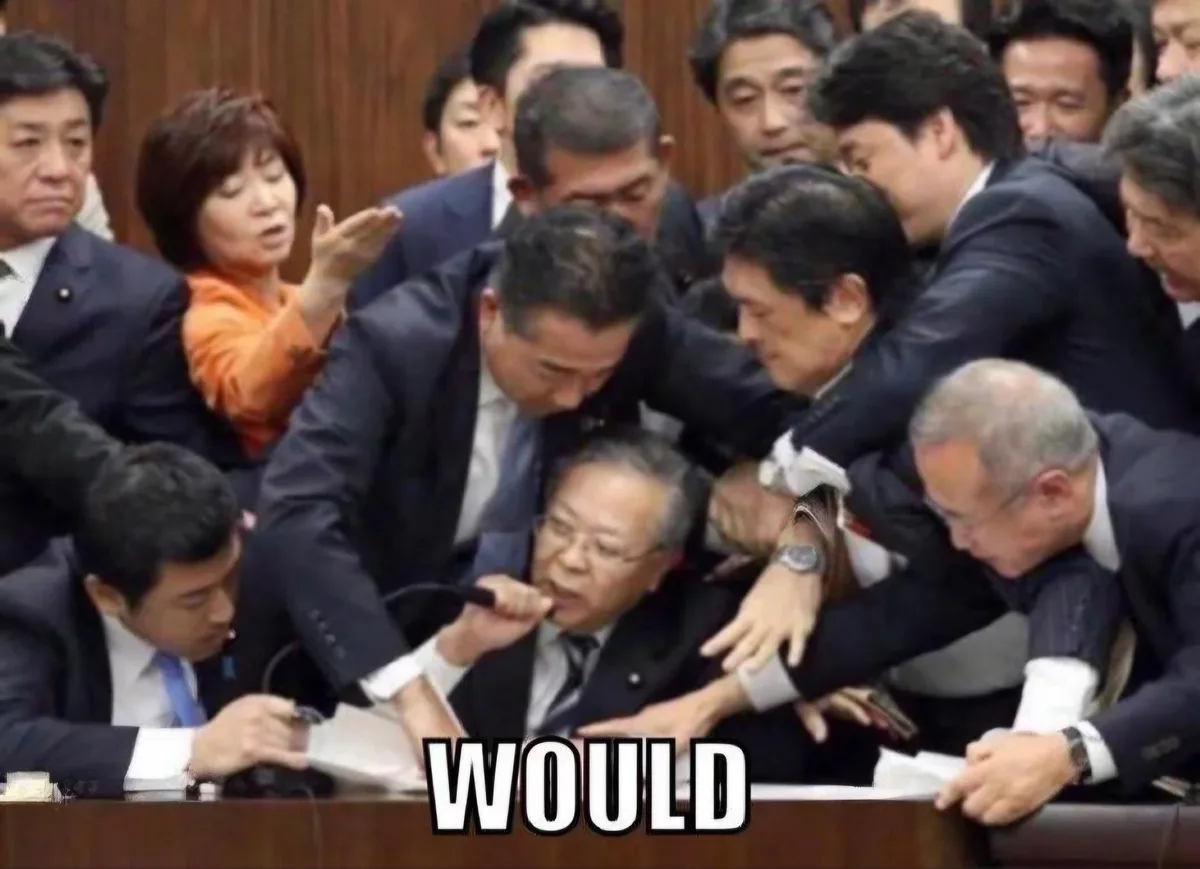 A crowded scene shows numerous men in dark suits surrounding and physically restraining an older man seated at a wooden…