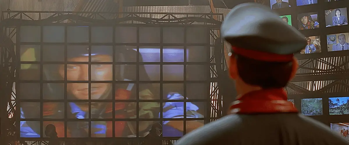 A sequence of images shows a man in a military-style uniform with a red collar and cap, standing in front of a wall of…