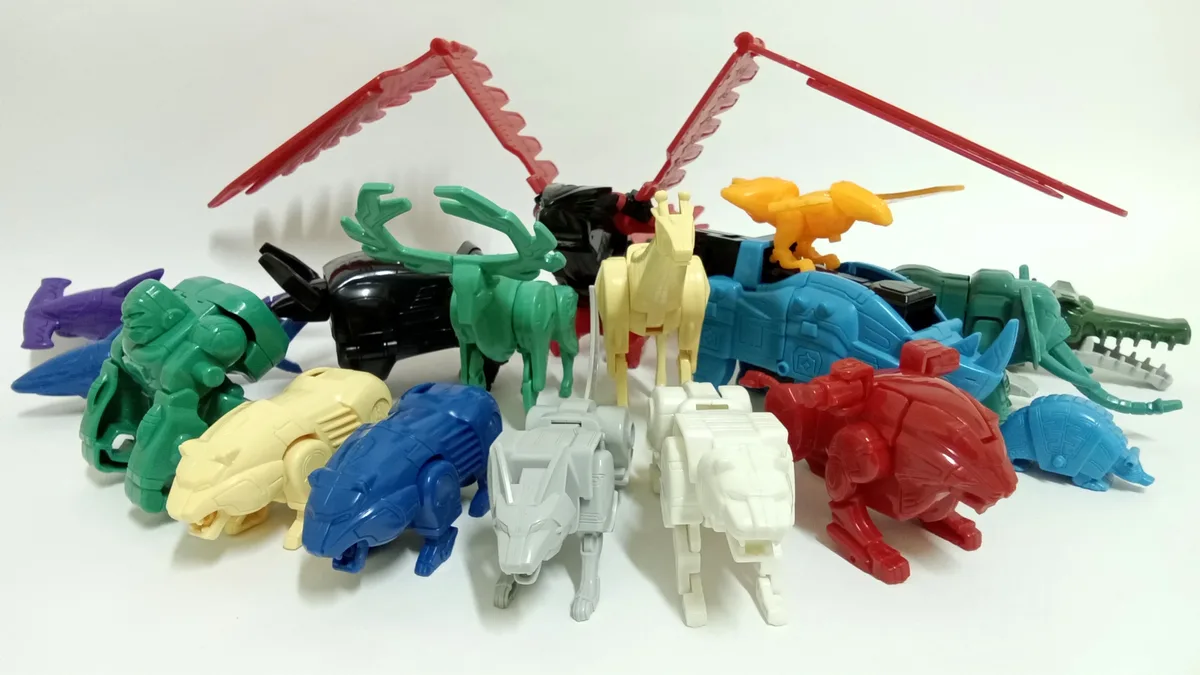 A collection of colorful, animal-themed transforming toy robots, including a green deer, a yellow horse, a red lion, and a…