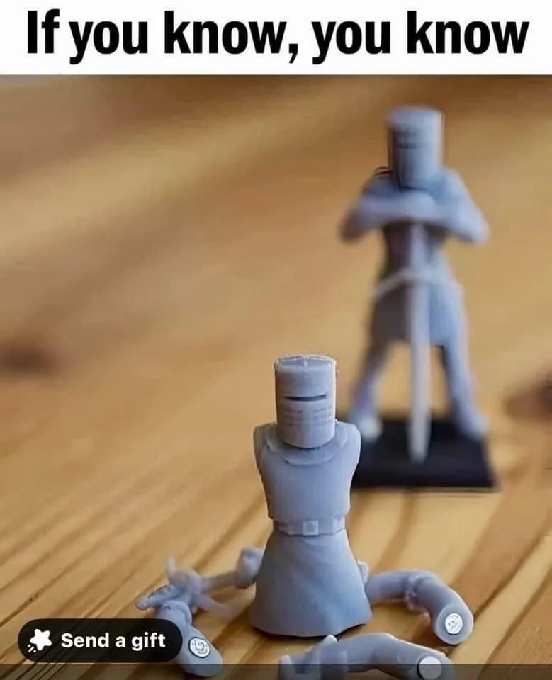 Two gray plastic knight figurines sit on a wooden floor; the foreground figure is missing limbs and has a detached head…
