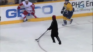 A sequence of six images shows a person in a black coat and red hat clumsily trying to play hockey on an ice rink, using a…