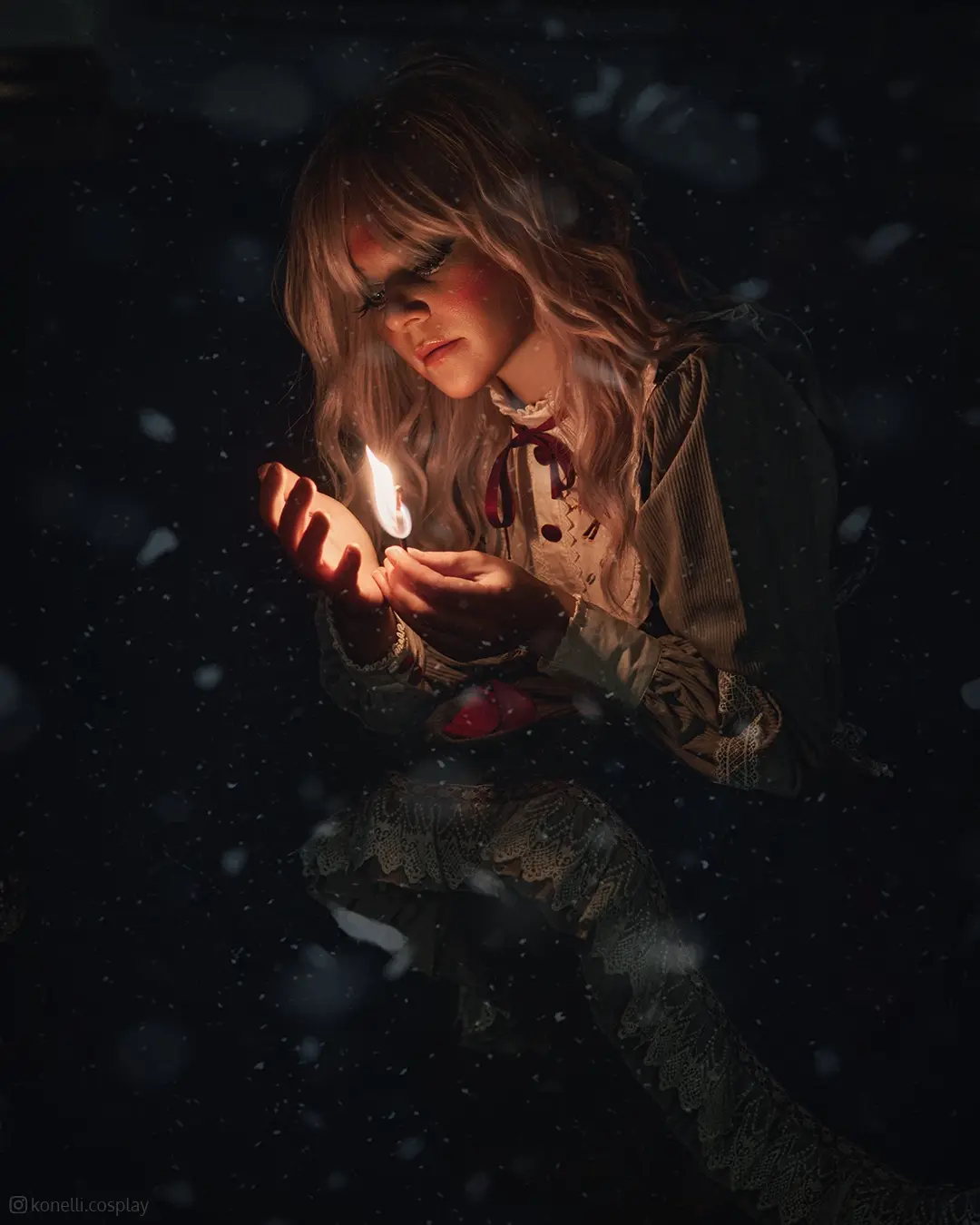 A person in a dark, snowy, gothic-style outfit holds a small flame in their cupped hands, looking down at it with a somber…