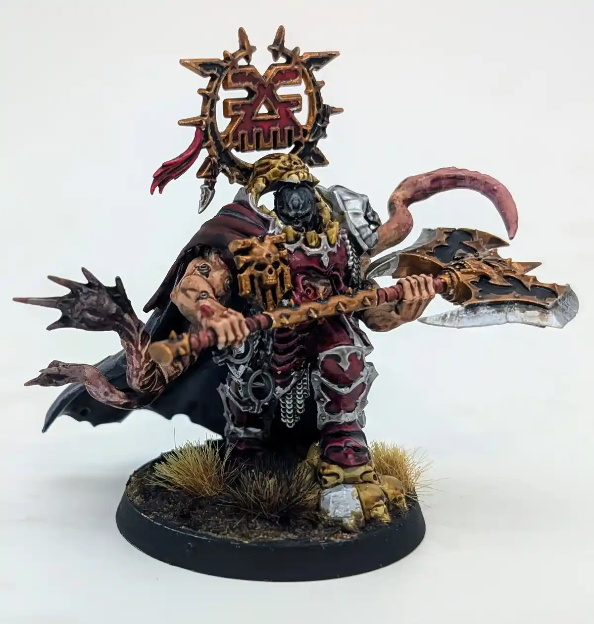 A heavily painted fantasy miniature of a demonic warlord with a skull-faced helmet, wielding a large ornate axe and a spiked…
