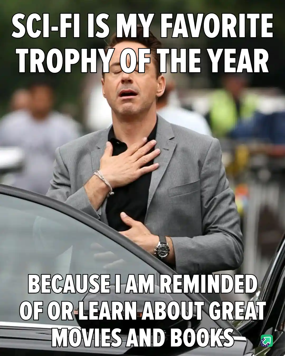 A man in a gray suit stands by a car with his hands on his chest, eyes closed, looking emotional. The overlaid text reads…