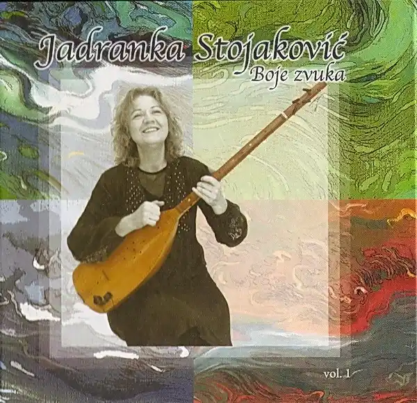 An album cover featuring a smiling woman with curly hair holding a stringed instrument against a colorful abstract…