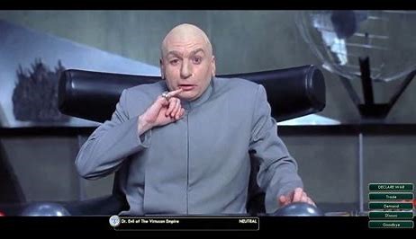 A bald man in a grey suit sits in a black chair, holding a cigarette to his lips with a surprised expression. Behind him is…