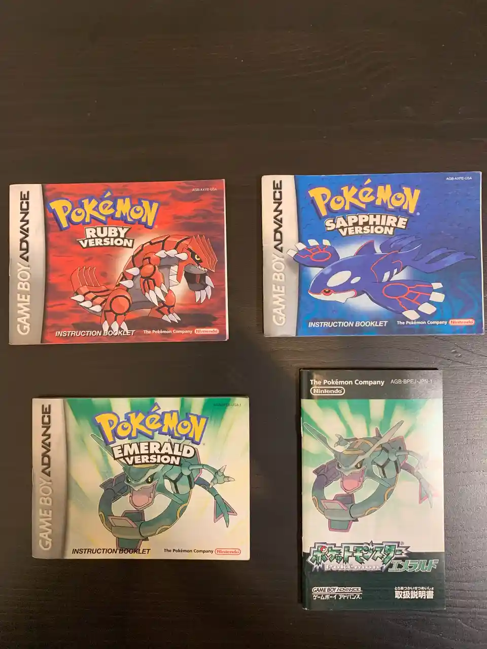 Four Pokémon Game Boy Advance instruction booklets are laid out on a dark surface: Ruby (featuring Gyarados), Sapphire…