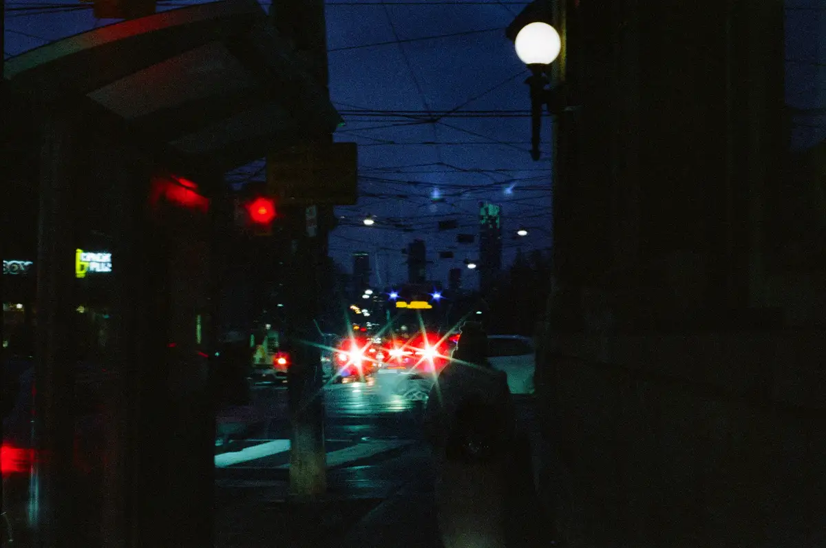 A dark, grainy night street scene with blurred car lights and a red traffic light, overlaid with the text 'i'm not late, i'm…