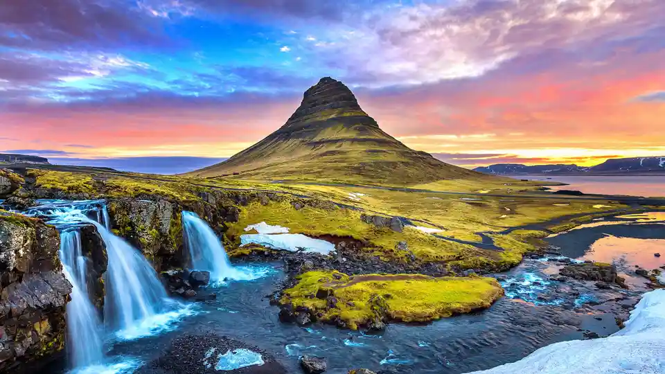 Iceland's iconic Kirkjufellsfoss waterfall lies at the base of majestic Kirkjufell mountain, its 1,500-foot peak piercing…