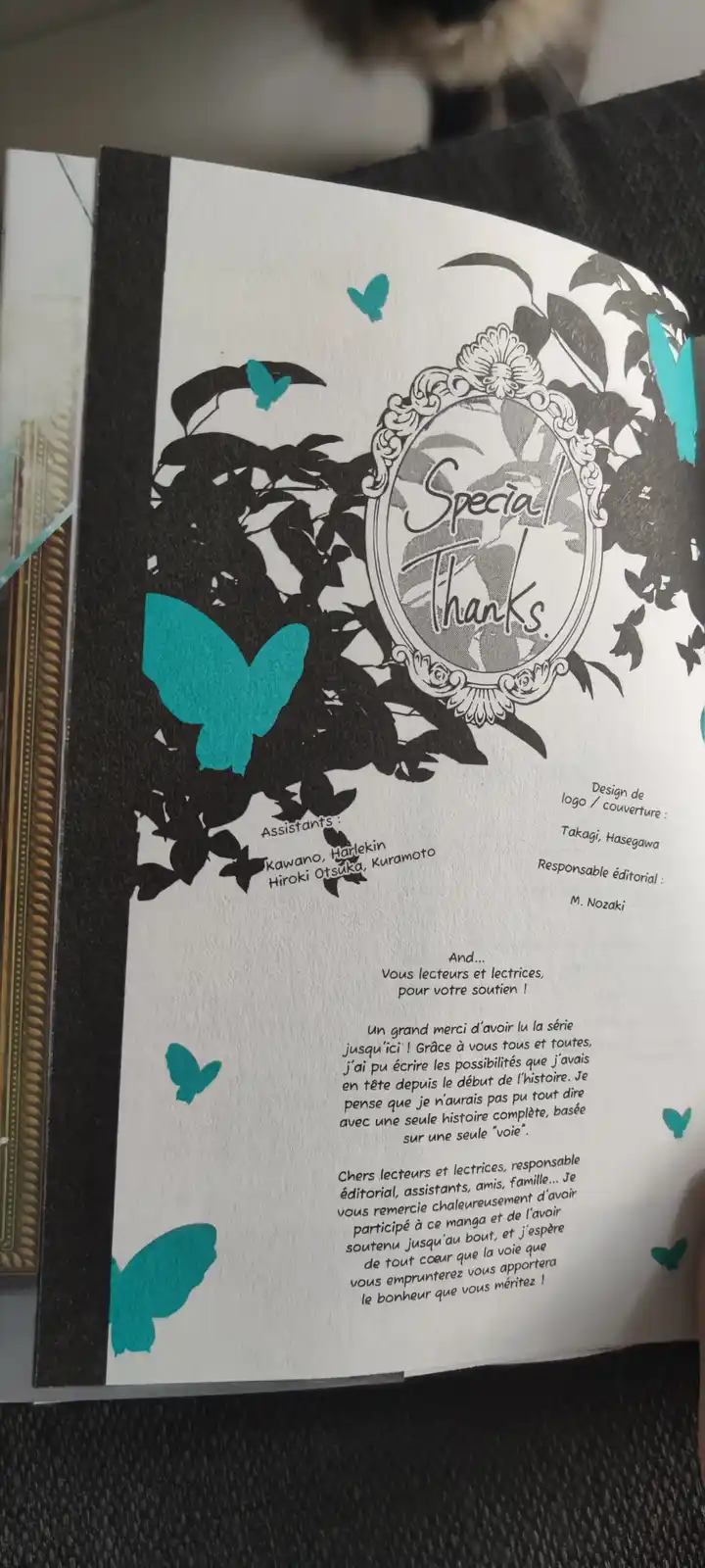 A close-up photo of a manga's 'Special Thanks' page, decorated with black silhouettes of leaves and bright teal butterflies…