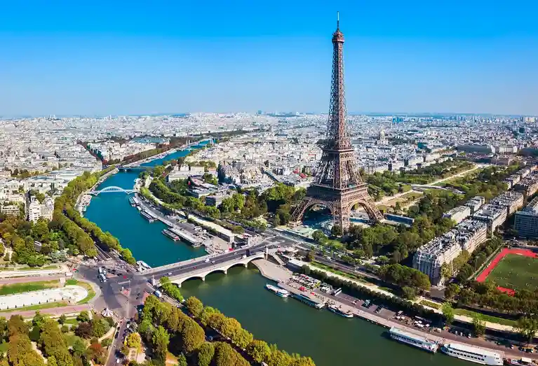 An aerial view of Paris, France, showcasing the Eiffel Tower, the Seine River, bridges, and surrounding cityscape under a…