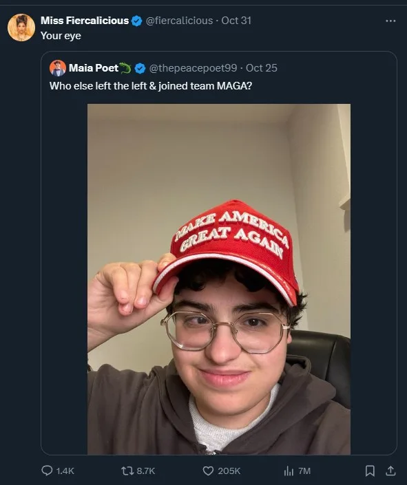 A young person with glasses and dark hair is smiling while wearing a red 'MAKE AMERICA GREAT AGAIN' cap and adjusting it…