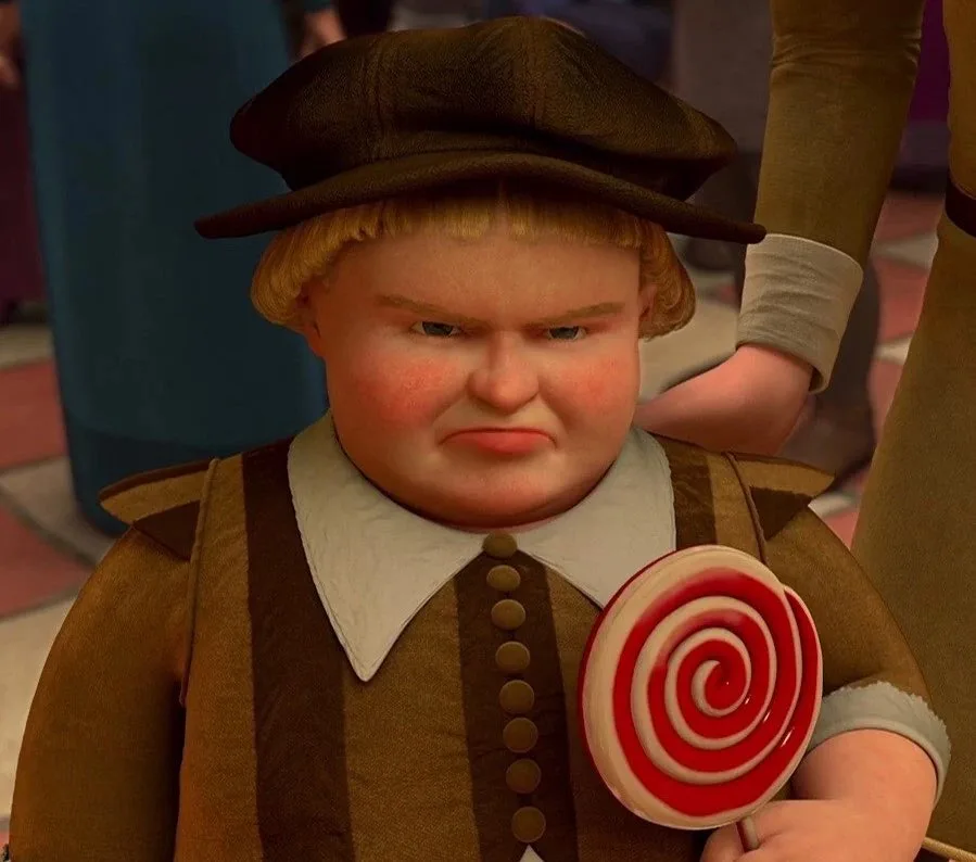 A close-up of a chubby animated boy with blonde hair, wearing a brown hat and brown vest over a white collar, holding a red…