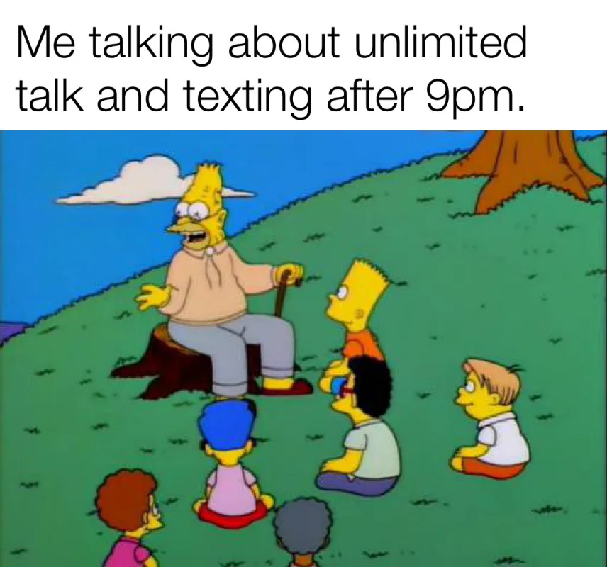 An older, elderly-looking Homer Simpson sits on a tree stump outdoors, gesturing animatedly while speaking to a circle of…