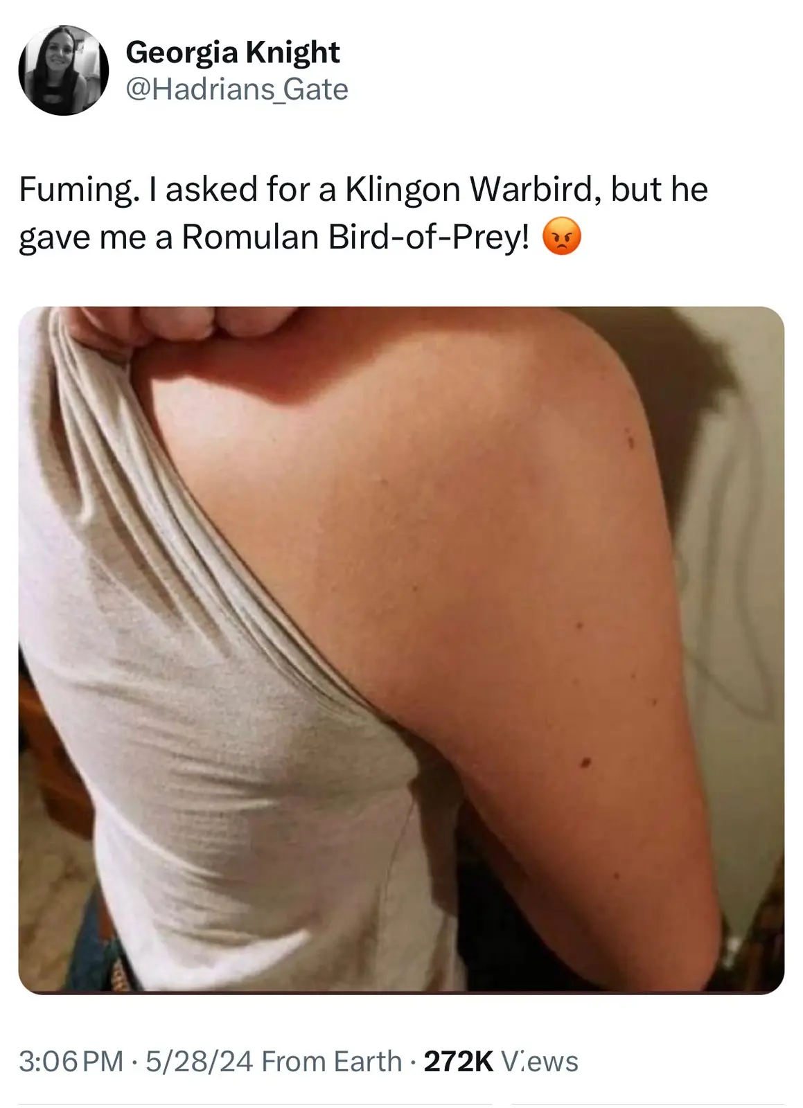 A person is shown from behind, pulling up the back of their light-colored tank top to reveal a bare shoulder and upper arm…