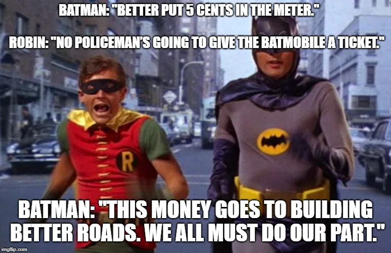 Two men dressed as Batman and Robin from the 1960s TV show stand on a city street. The Batman figure is on the right…