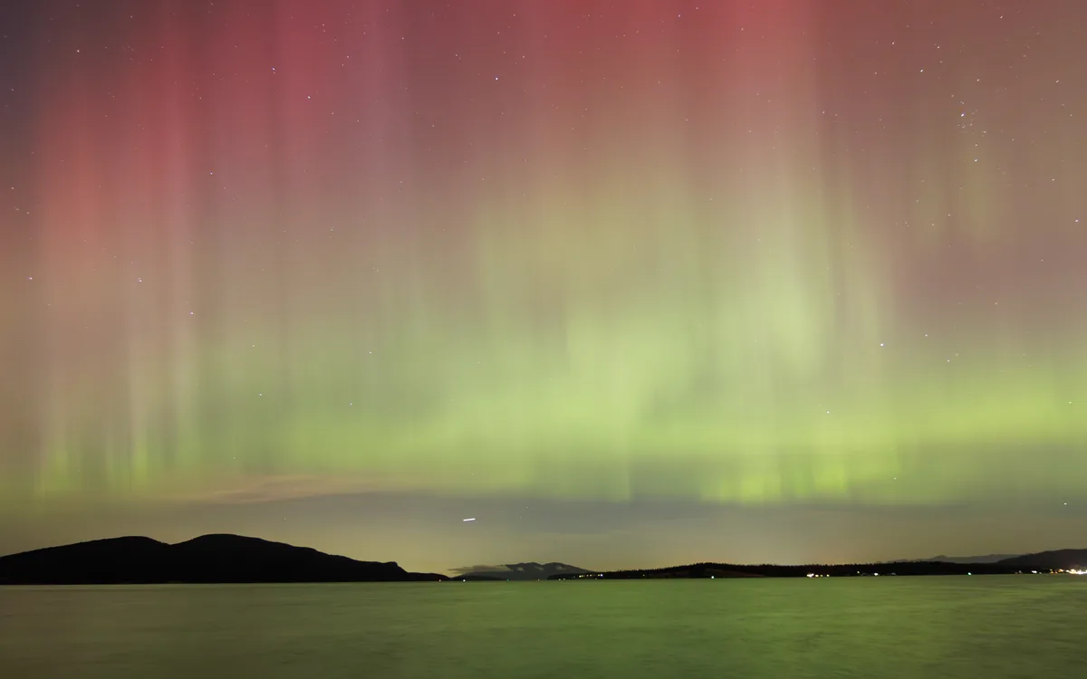 A stunning photograph of the aurora borealis, with vibrant green and pink curtains of light dancing across a starry night…