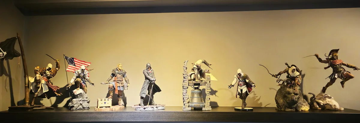 A row of detailed Assassin's Creed action figures displayed on a shelf, each in unique poses and outfits representing…