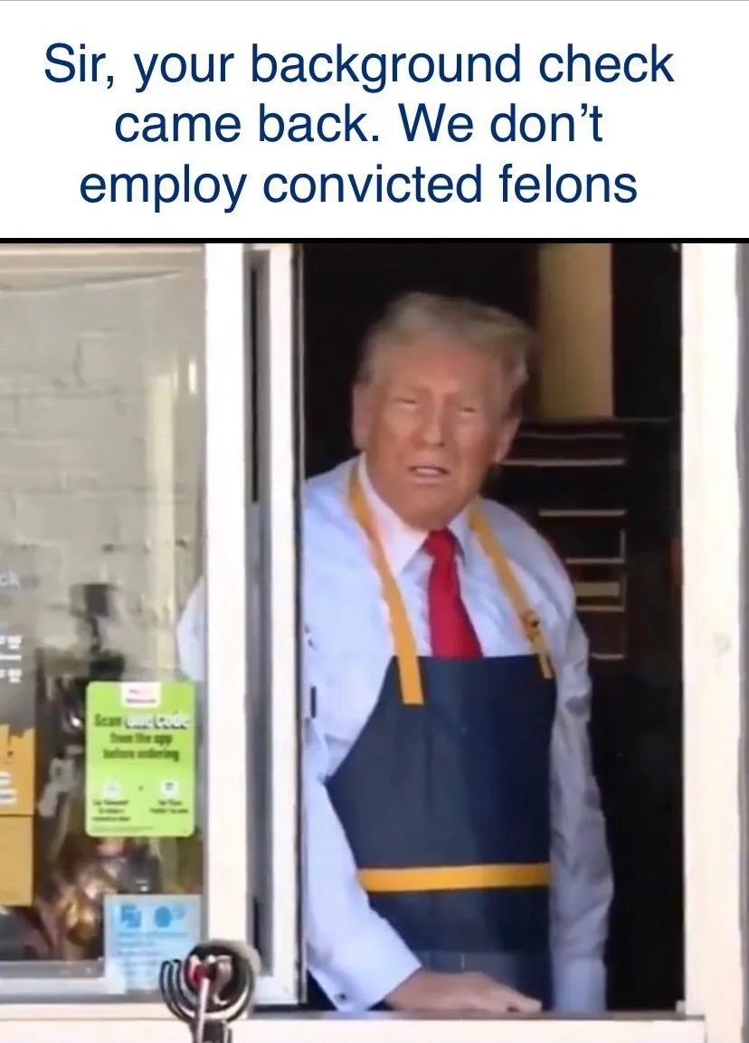 A man with blonde hair, wearing a light blue shirt, red tie, and a dark blue apron with yellow straps, leans out of a…