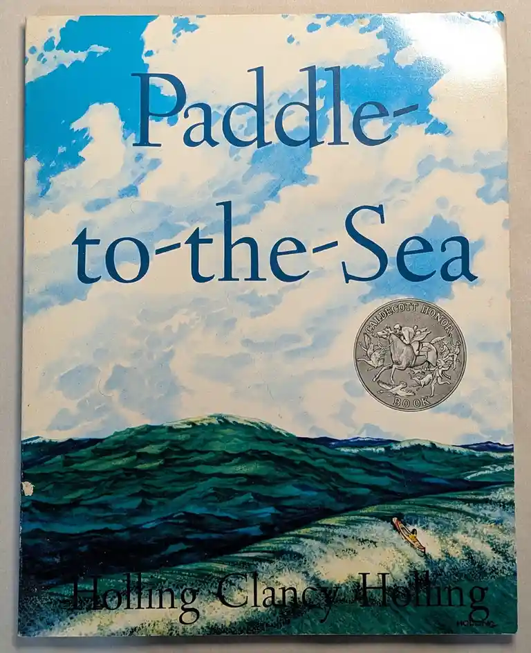 The image shows the cover of the children's book 'Paddle-to-the-Sea' by Holling Clancy Holling. The cover art depicts a…