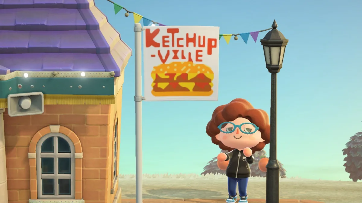 A screenshot from Animal Crossing showing a character standing beside a lamppost under a banner that reads 'KETCHUP-VILLE'…