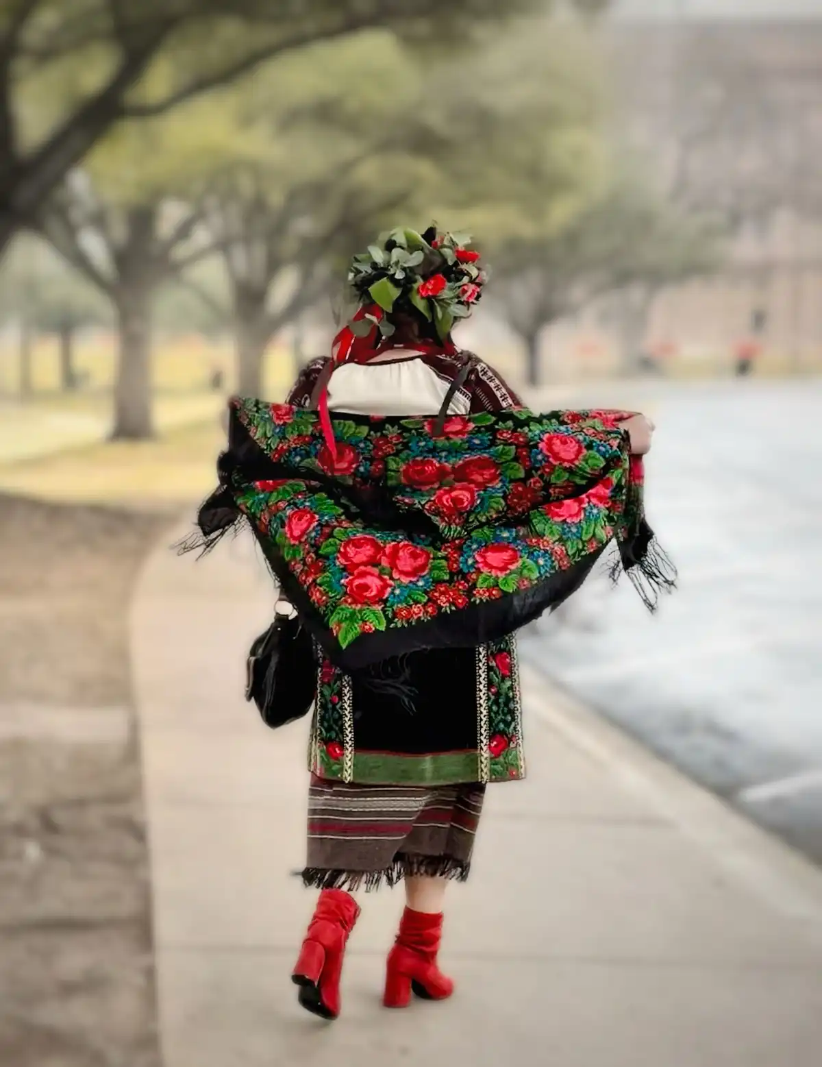 A person viewed from behind walks away down a sidewalk, wearing a vibrant, traditional-style outfit with a floral-patterned…