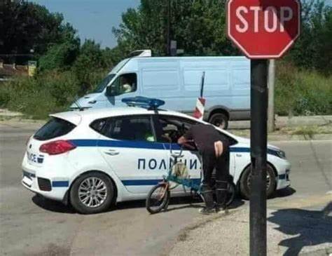 A police officer in a white Russian police car with 'ПОЛИЦИЯ' written on the side is leaning out of the driver's window to…