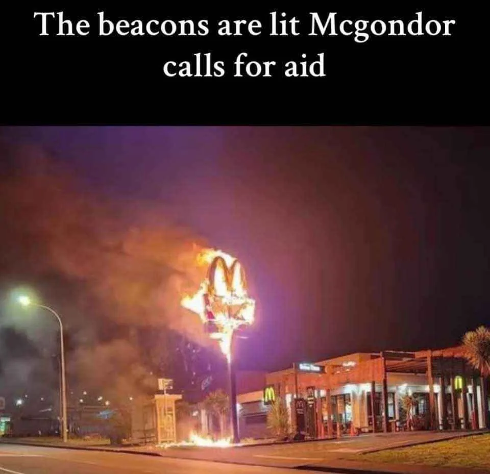 A nighttime photo shows a McDonald's restaurant with its iconic golden arches sign on fire, emitting flames and smoke…
