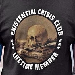 A black t-shirt displays a circular graphic featuring a human skull resting atop a stack of old, worn books. The text…