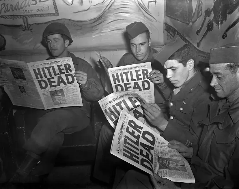 Four soldiers in military uniforms sit together, each holding a copy of 'The Stars and Stripes' newspaper with the bold…