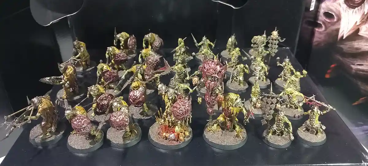 A collection of intricately painted miniature fantasy figurines, mostly green-skinned warriors with ornate armor and…