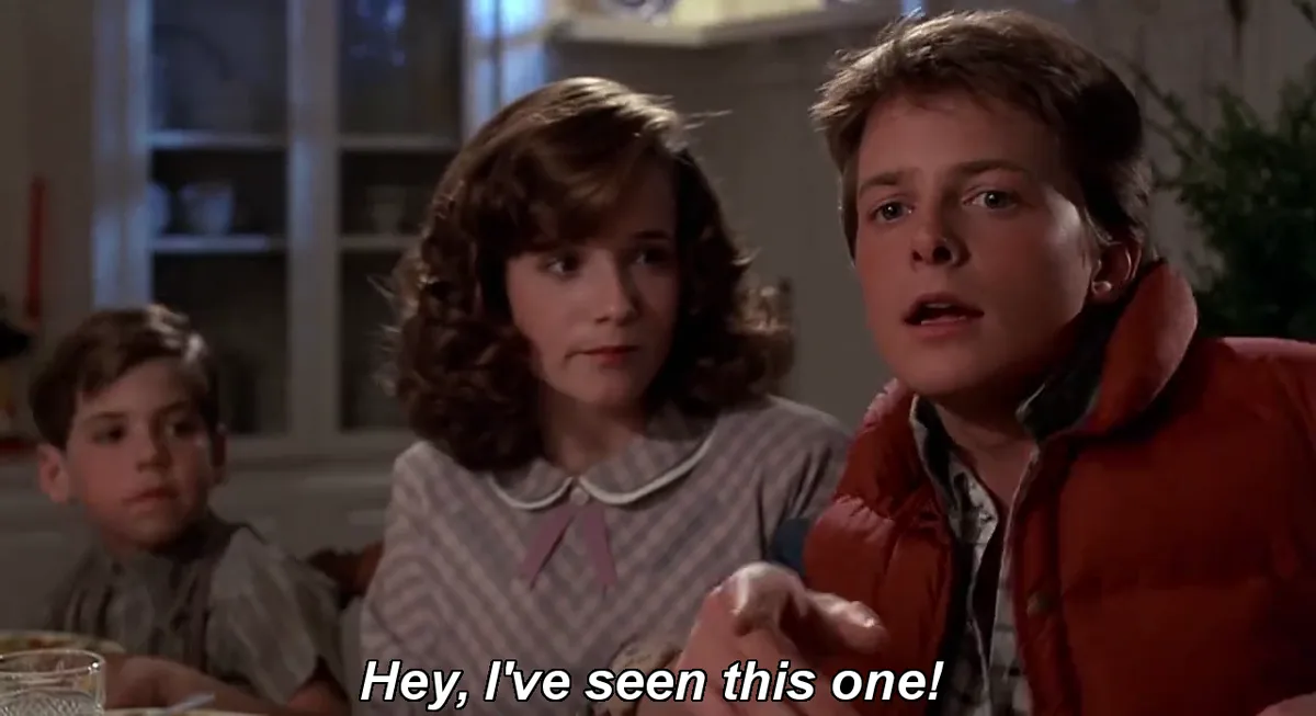 A still from the movie 'Back to the Future' shows three children at a dinner table. The boy on the right, wearing a red…