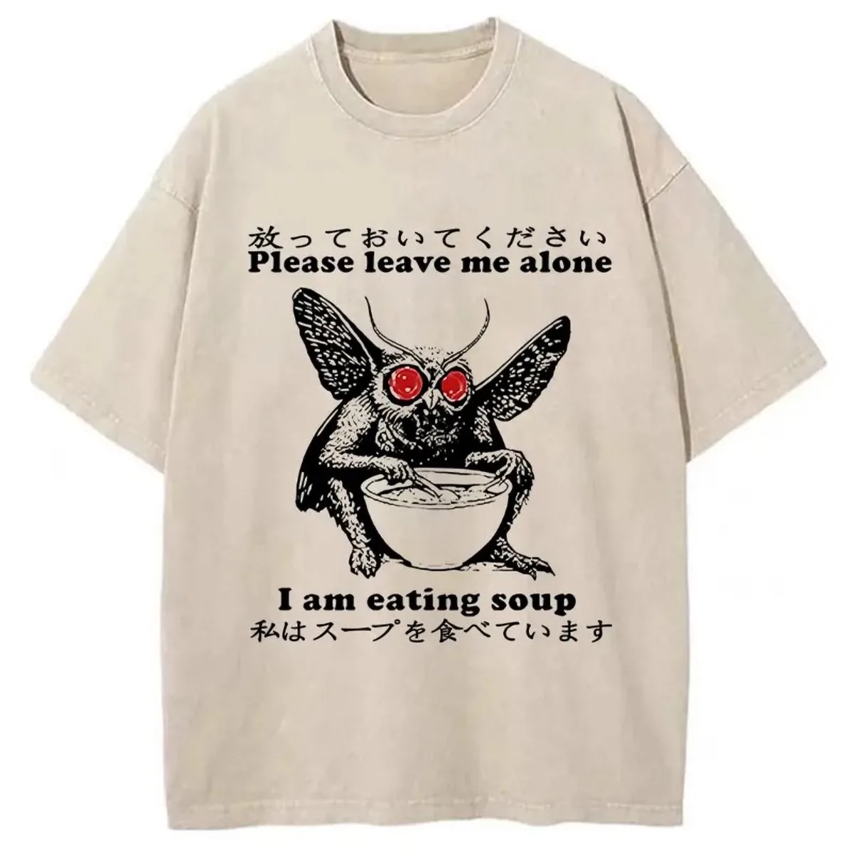 A beige t-shirt features a black-and-white illustration of a winged, red-eyed monster with horns, sitting and eating from a…