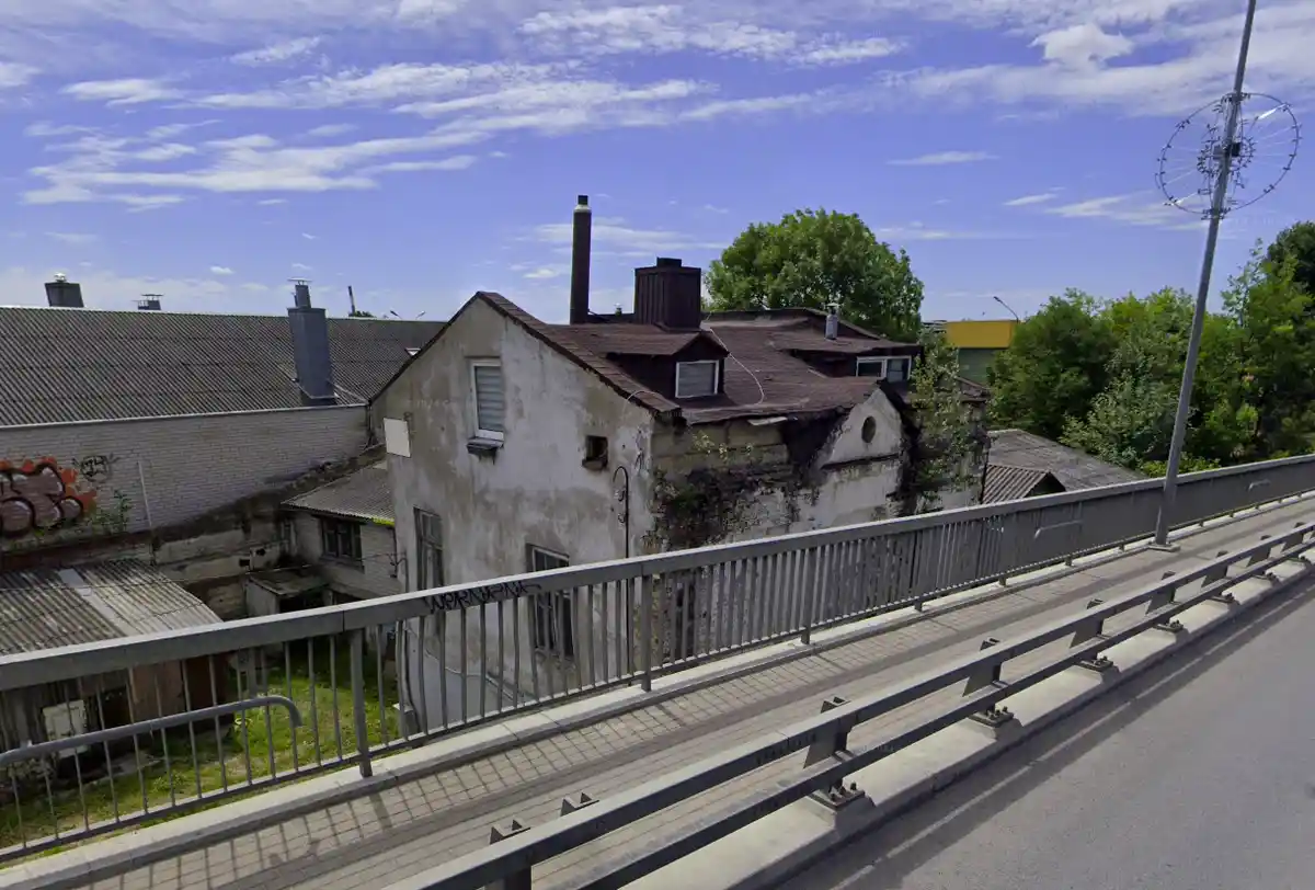 A Google Street View image shows a weathered, dilapidated building with peeling paint and a rusty roof, viewed from a…