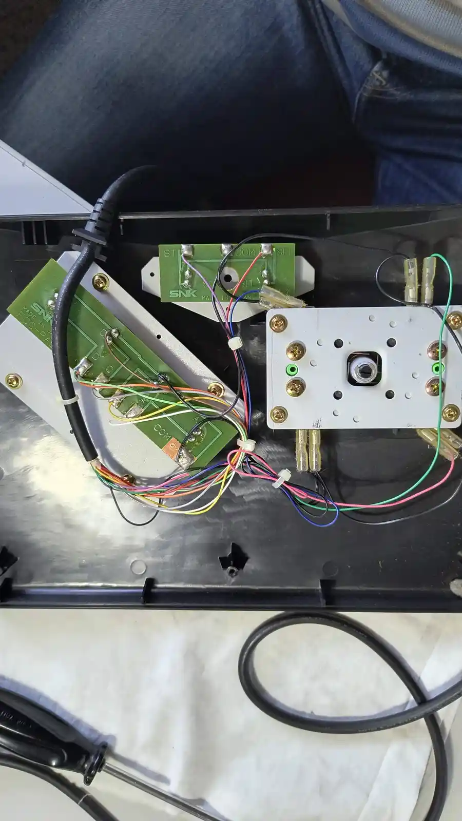 The image shows the internal wiring and circuit boards of an arcade game machine, with visible green circuit boards labeled…