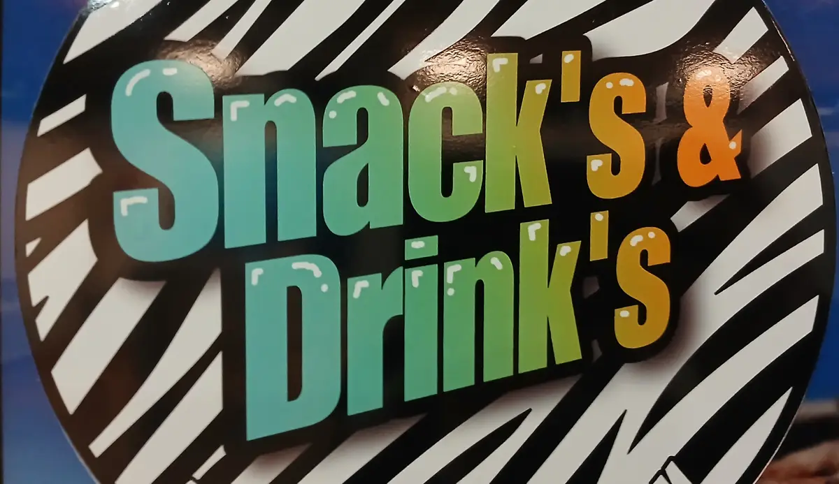 A close-up of a circular sign with a black and white diagonal striped border. The text 'Snack's & Drink's' is displayed in…