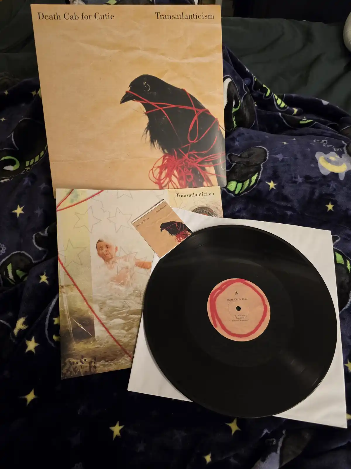A photo of the Death Cab for Cutie album 'Transatlanticism' vinyl record, showing the album cover with a black bird wrapped…