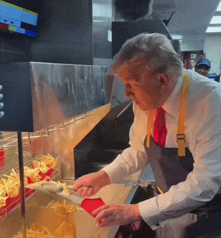 A composite image shows former president Donald Trump wearing a white shirt, red tie, and yellow apron, standing behind a…