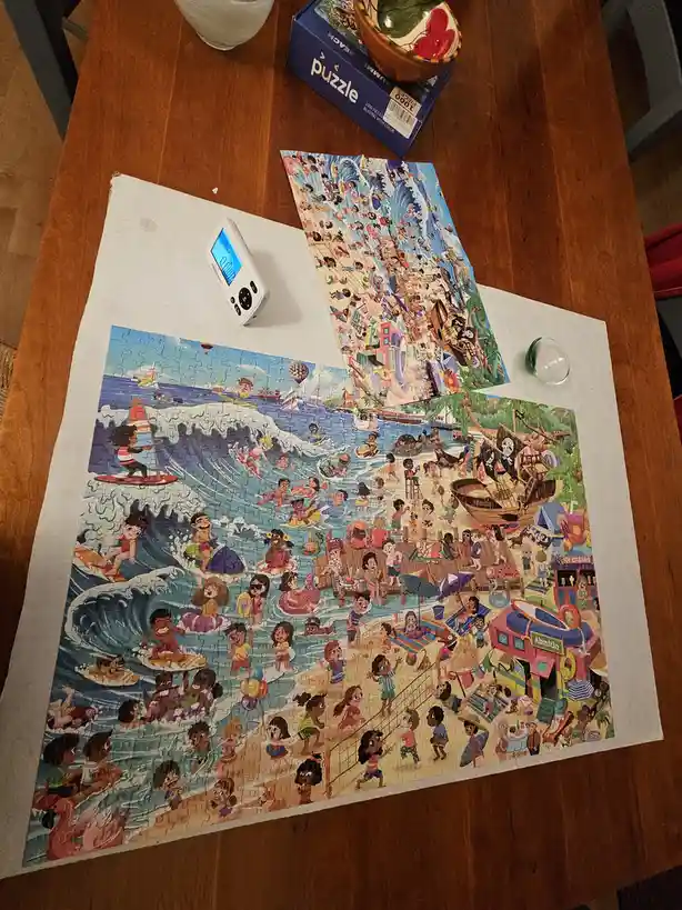 A partially completed 1000-piece beach-themed jigsaw puzzle is spread on a wooden table, with a digital timer showing…
