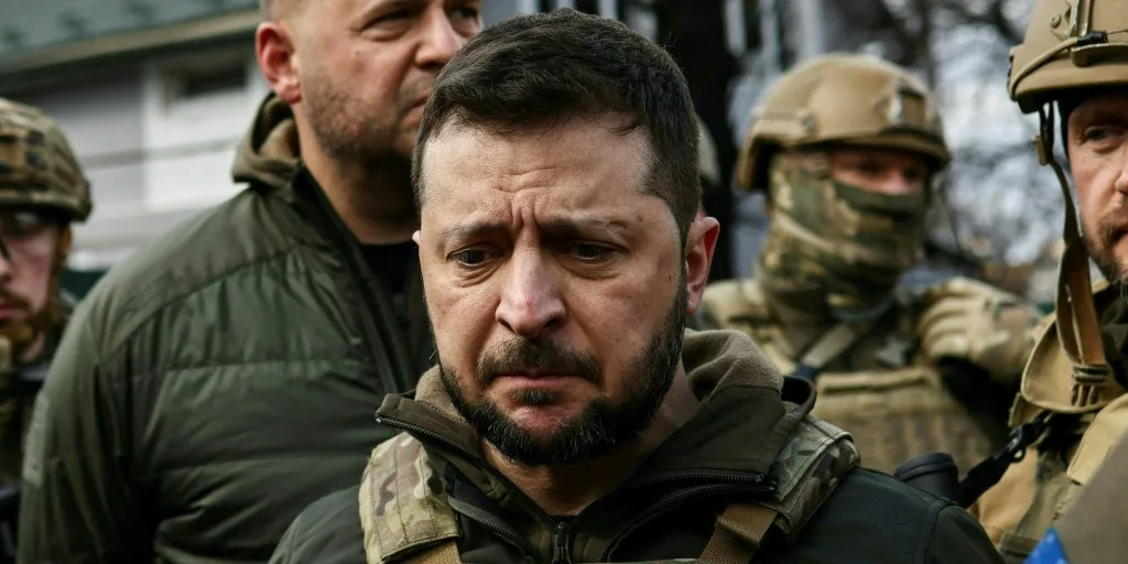 A close-up photo of a man with a serious, tearful expression, surrounded by soldiers in military gear. The overlaid text…