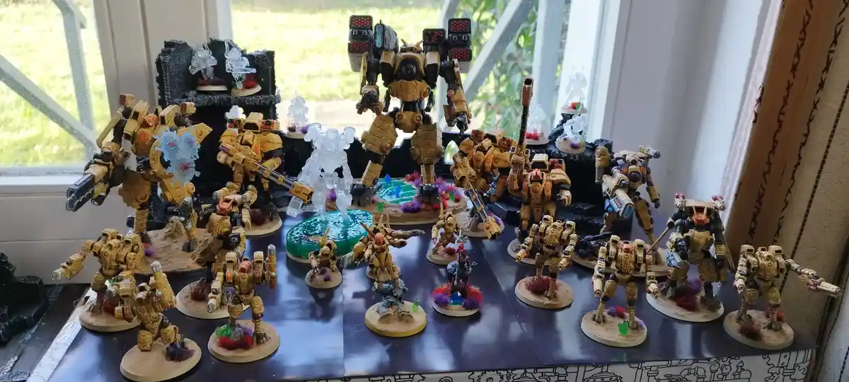 A collection of painted, yellow and black armored miniature figures, mostly resembling giant robots or mechs, are arranged…