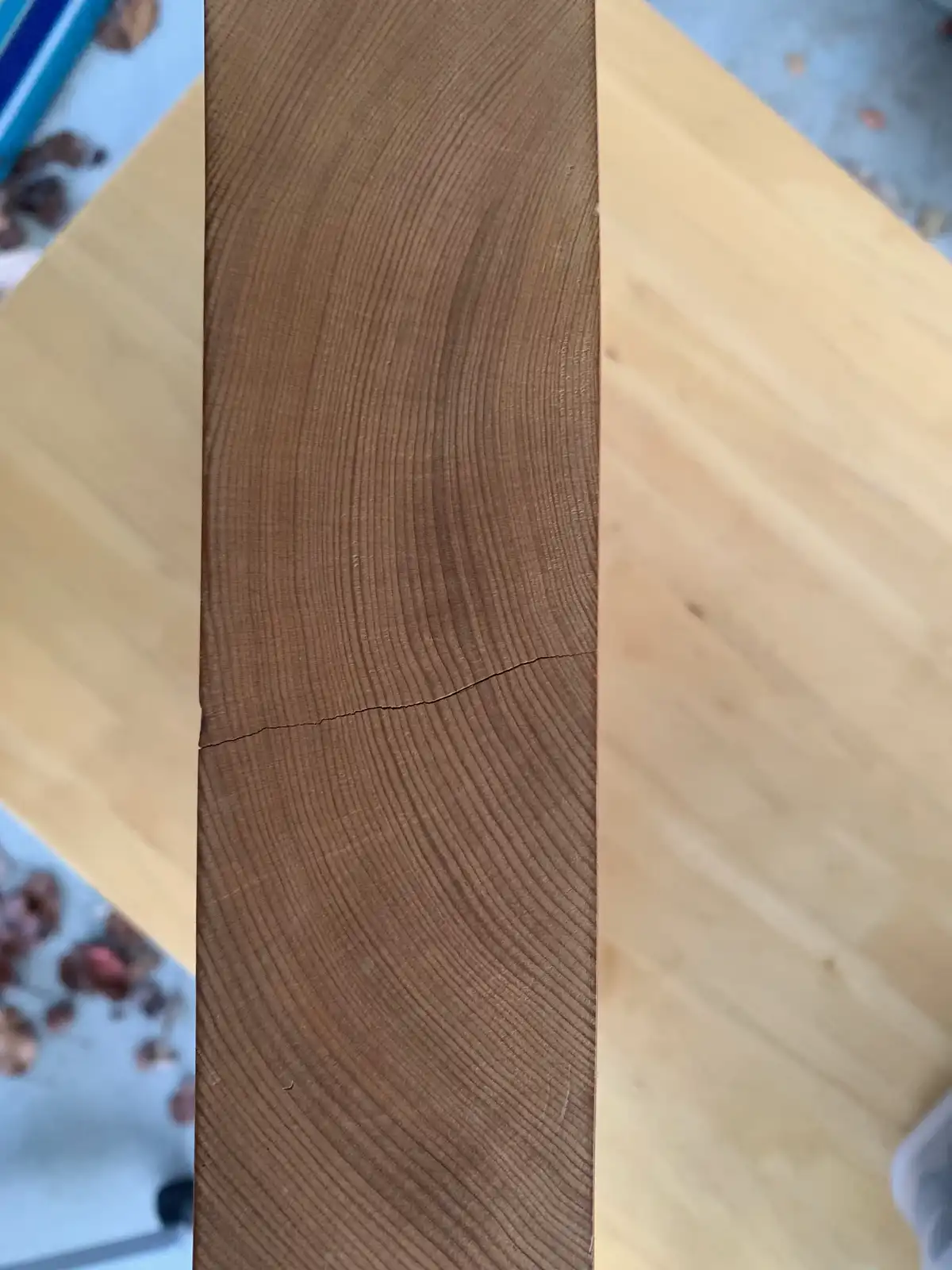 A close-up photo shows a vertical wooden plank with a prominent, dark crack running horizontally across its center, set…