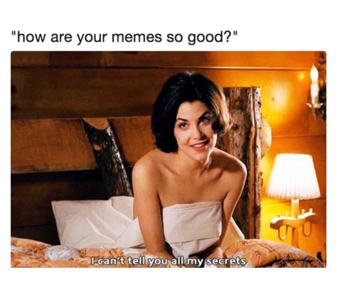 A woman with short dark hair sits on a bed wrapped in a white towel, smiling coyly at the camera. The scene is warmly lit…