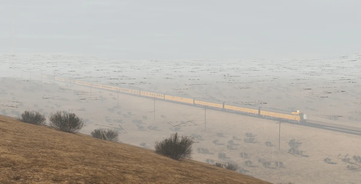 A long yellow train travels across a vast, hazy, and barren landscape with sparse vegetation and power lines. The image has…